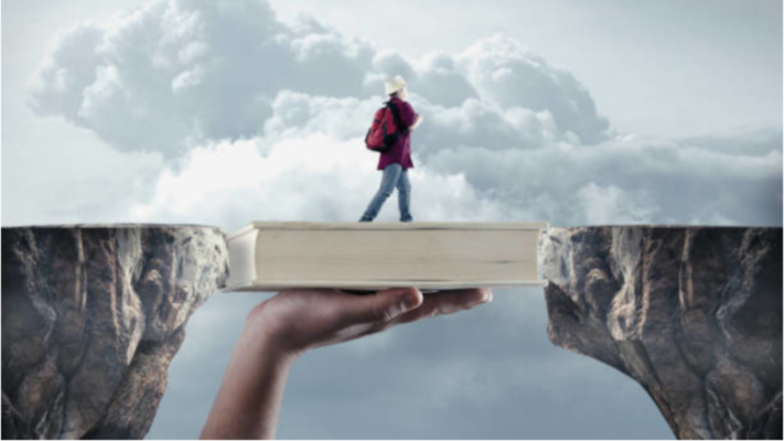 A person walking across a bridge over a ravine. The bridge is a book held up by a giant hand. 